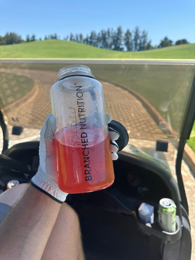 Branched Nutrition bottle with a pink drink on the golf course