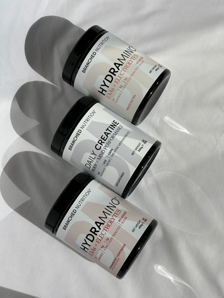 HYDRAMINO in Strawberry Lemonade and Peach Ice Tea with Daily Creatine on sunlit white fabric